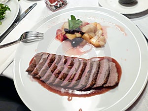 Chopped slices of grilled meat on a white plate. An example of serving dinner