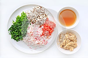 Chopped vegetables with soup and mash fish on white plate against white background