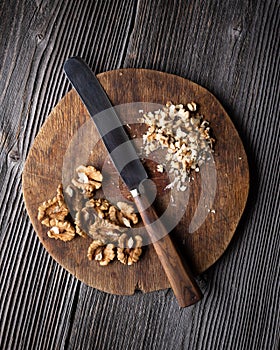 Chopped walnuts and knife on wooden plate photo