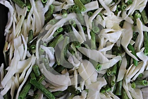 Chopped white cabbage with green beans in the pan before stewing
