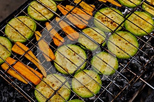 Chopped zucchini and carrots roasting on fire seasoned with aroma herbs and spices. Delicious fresh vegetables grilling