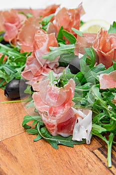 Chopping board with aragula and raw ham