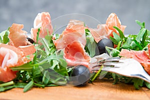 Chopping board with aragula and raw ham