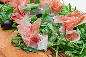 Chopping board with aragula and raw ham