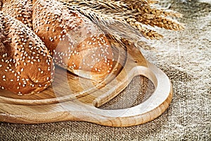 Chopping board baguette wheat ears on vintage sacking background