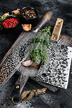 Chopping board and meat cleaver with knife. Black background. Top view
