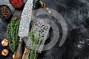 Chopping board and meat cleaver with knife. Black background. Top view. Copy space
