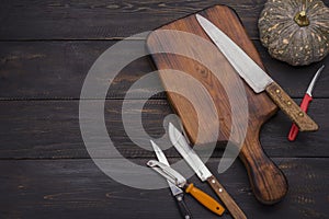 Chopping board with paring knife, carving knife and pumpkin placed on old wooden floor. In the kitchen or in the restaurant where