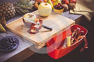 Chopping Board with Red Waste Container with Fresh Fruits Background