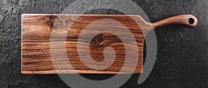 Chopping cutting board on dark stone background. Wooden texture. Top view, toning