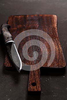 Chopping cutting wooden board and knife on dark concrete background