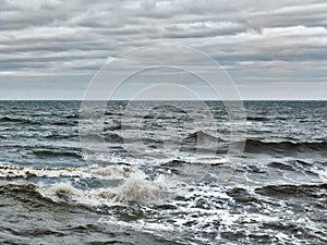 Choppy atlantic ocean waves with surf and grey winter clouds