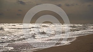 Choppy ocean waves crash onto sandy beach under stormy sky. Rough sea footage ideal for meteorology, nature docs