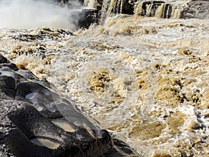 The choppy waters of the Yellow river with eroded rocks photo