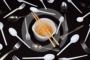 Chopsticks in bowl with noodles on black background