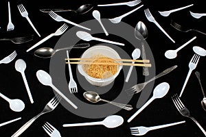 Chopsticks in bowl with noodles on black background