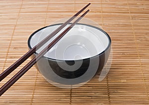 Chopsticks with ceramic bowl on bamboo mat