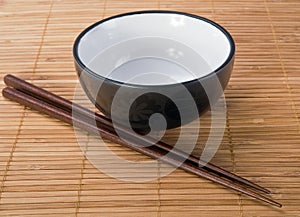 Chopsticks with ceramic bowl on bamboo mat