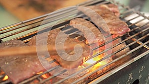 Chopsticks flipping sliced beef on Japanese traditional stove called ` Hida charcoal stove`. close up Japanese Yakiniku.