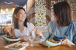 Chopsticks, girl friends and funny joke with restaurant food, noodles and cafe happy from bonding. Asian women, eating
