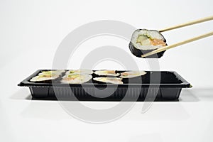 chopsticks grabing a piece of sushi from a sushi set