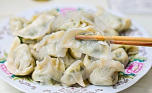 Chopsticks Pick Up Boiled Chinese Dumplings from a Plate. photo