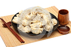 Chopsticks Pick Up Boilded Chineses Dumplings from a Plate. The Dumpling, called Jiaozi in Chinese, is a popular traditional Chine