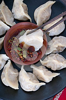 Chopsticks pick up the dumplings on the plate and dip them into the vinegar and chili sauce