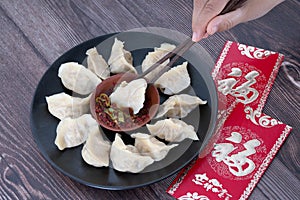 Chopsticks pick up the dumplings on the plate and the red envelopes under the plate.The Chinese meaning in the picture is `happine