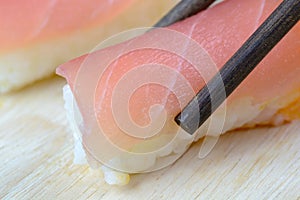 Chopsticks pinch fresh tuna sushi