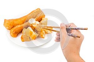 Chopsticks reaching for a piece of You Tiao, or fried bread stic