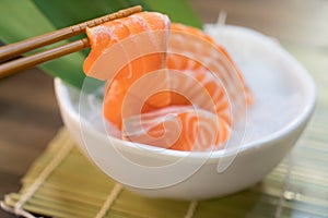 Chopsticks with Salmon sashimi with Salmon sashimi on ice in with bowl. japanese food in Asian restuarant