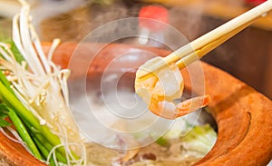 Chopsticks and tongs of hot prawns put up to eat Shabu Hot Pot. Prepare eating food