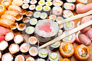 Chopsticks with tuna roll over set of sushi