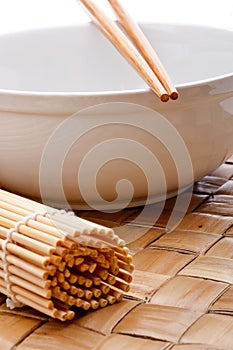 Chopsticks on a white bowl with a sushi mat