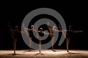 A choreographed dance of a group of graceful pretty young ballerinas practicing on stage in a classical ballet school.