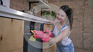 Chores, young housekeeper female in rubber gloves for cleaning wipe dusty furniture