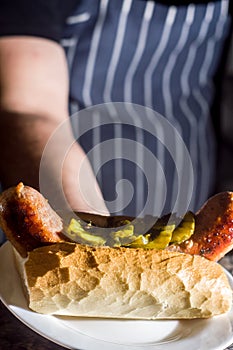 choripan, bread with sausage and pickles on a plate with dark background and copy space