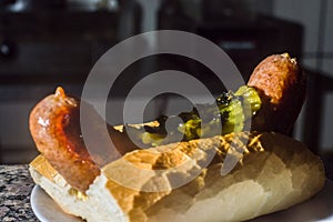 choripan, bread with sausage and pickles on a plate with dark background and copy space