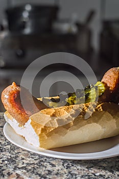 choripan, bread with sausage and pickles on a plate with dark background and copy space