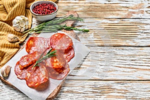 Chorizo sausage thin cut on a cutting board. Spanish salami with spices, paprika, pepper. Spicy food. White background. Top view.