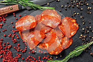 Chorizo sausage thin cut. Spanish salami with spices, paprika, pepper. Spicy food. Black background. Top view