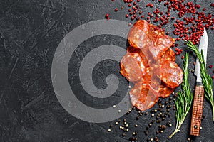 Chorizo sausage thin cut. Spanish salami with spices, paprika, pepper. Spicy food. Black background. Top view. Copy