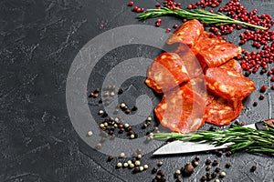 Chorizo sausage thin cut. Spanish salami with spices, paprika, pepper. Spicy food. Black background. Top view. Copy space