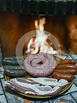 Chorizos, sausages, sausage, pork belly and blood sausage with the fire of the fireplace out of focus in the background