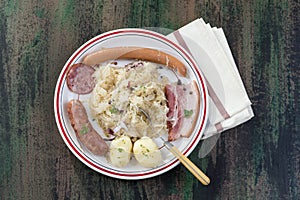 Choucroute garnie, a typical alsacian plate, with sausages, bacon, sauerkraut and potatoes on wooden background