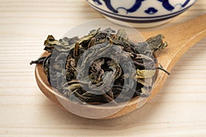 Choui Fong dried tea leaves close up on a wooden spoon