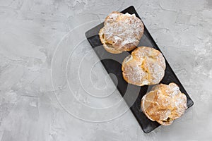 Choux Bun with whipped cream and sugar powder on top. Choux pastry dessert. French cream puff