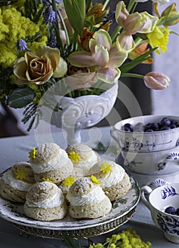 Choux Buns with Craquelin crispy cream puffs filled cream on a table decorated with spring flowers