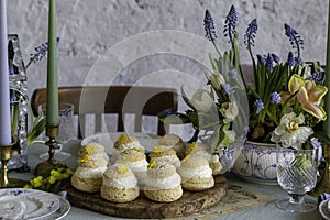 Choux Buns with Craquelin crispy cream puffs filled cream on a table decorated with spring flowers photo